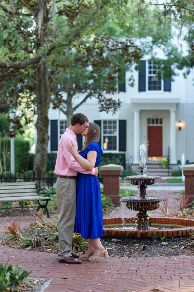 Couple kissing in front of small fountain in Celebration Florida Orlando for their engagement photos