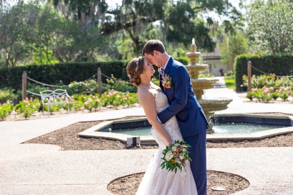 Bride and Groom kissing in front of fountain in the rose garden at Leu Gardens Orlando after their elopement