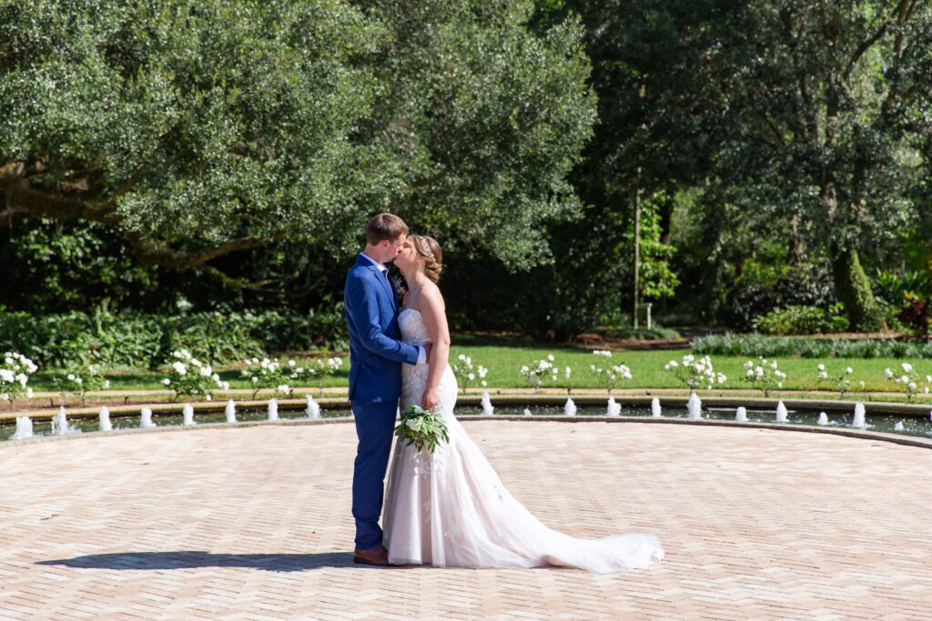 Bride and Groom kissing in front of fountain in the rose garden at Leu Gardens Orlando after their elopement 