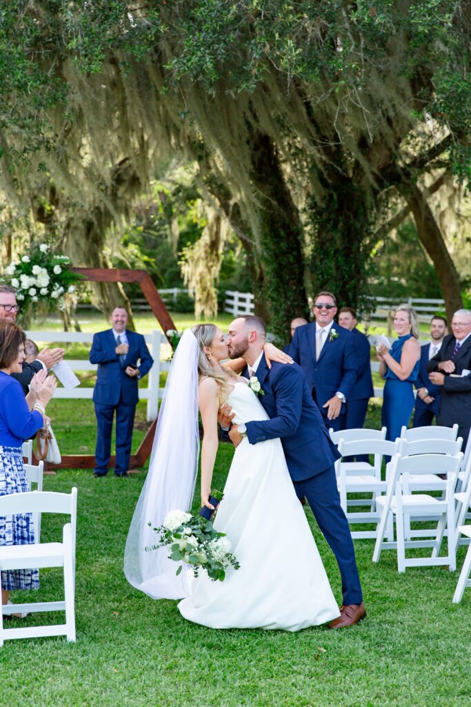 Bride and Groom kiss in aisle full of wedding guests to celebrate their micro wedding at Bramble Tree Estate, Florida