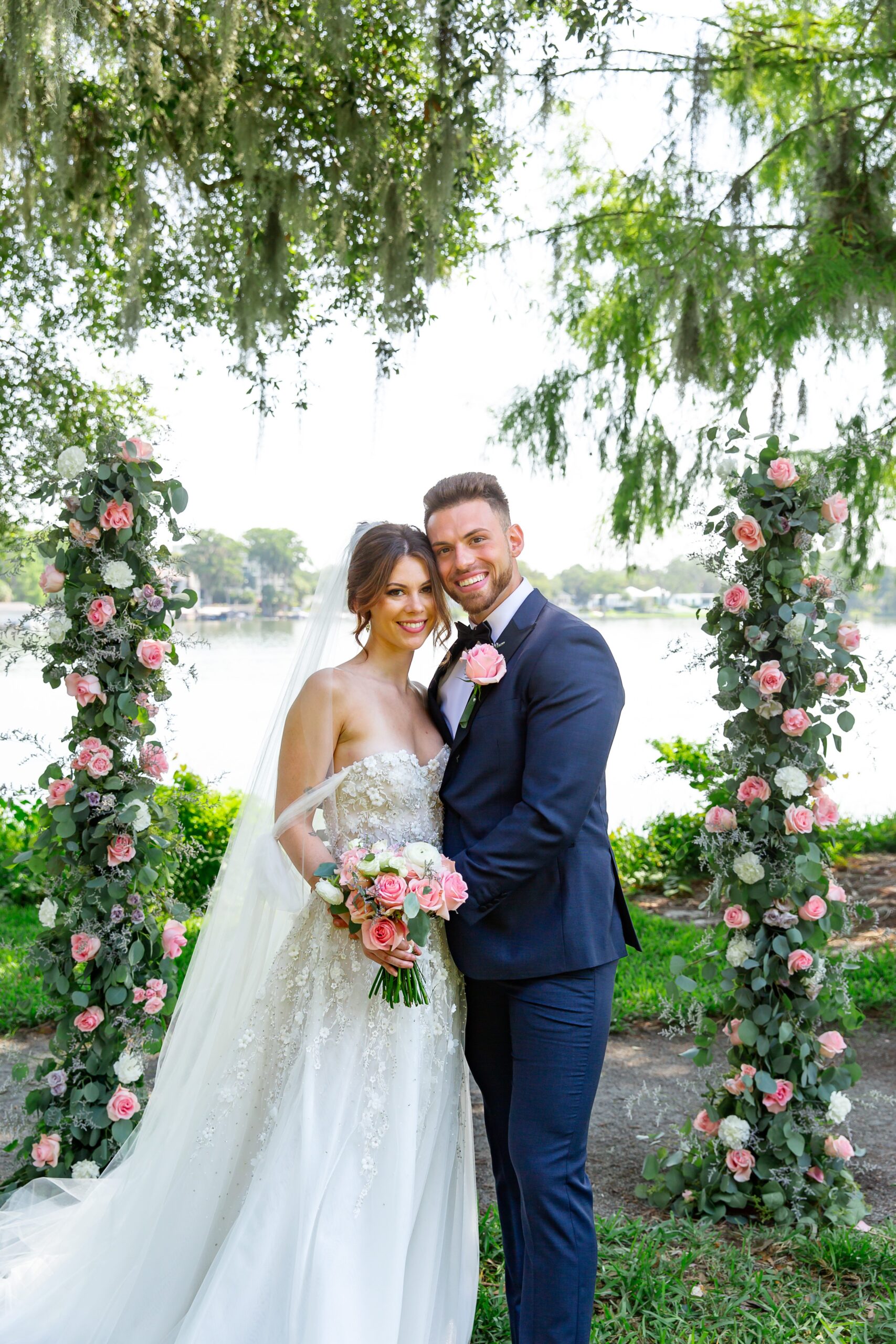Bride and Groom posing for photo in front of ceremony arch at Rollins College in Winter Park Florida after their elopement