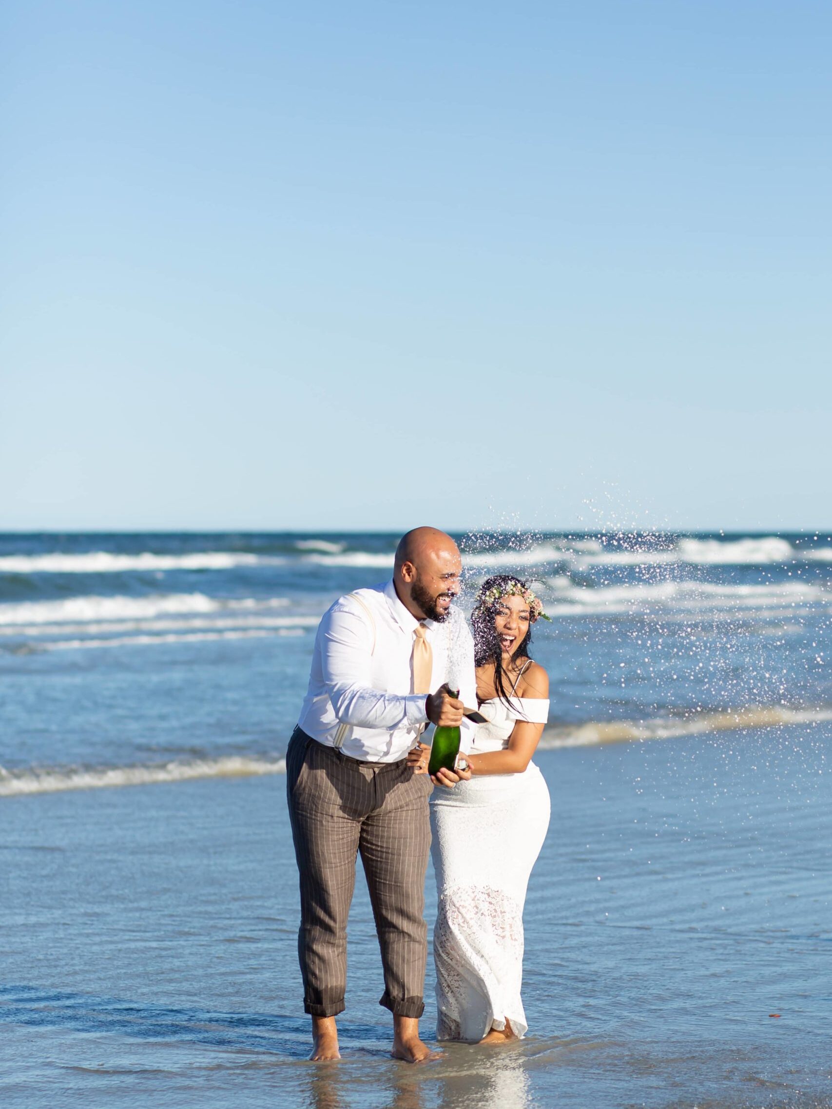 Bride & Groom doing a champagne pop in the ocean to celebrate elopement