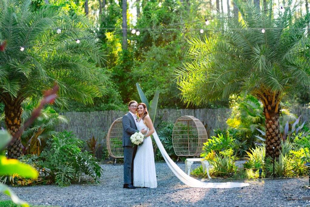 Bride and Groom standing in front of tropical garden at sunset at the Pinery wedding venue in Florida