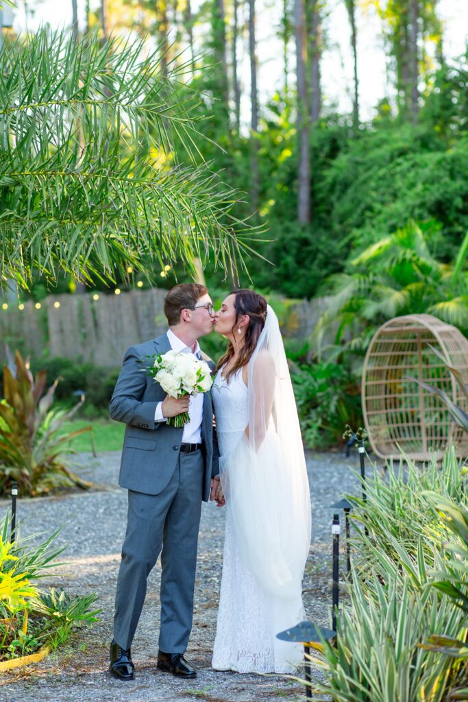 Bride and Groom kissing in tropical garden at sunset at the Pinery wedding venue in Florida