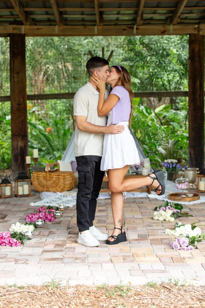 Couple kissing in front of pop up picnic after proposal at Mead Botanical Garden in Orlando