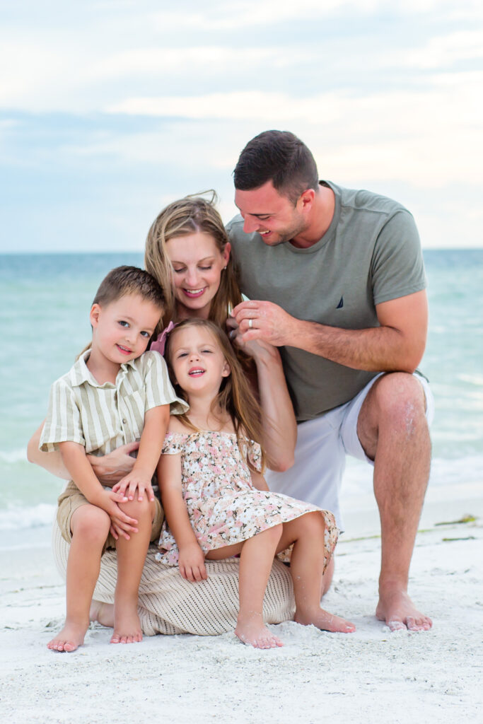 Family kneels on the beach at sunset for their Anna Maria Island photo session