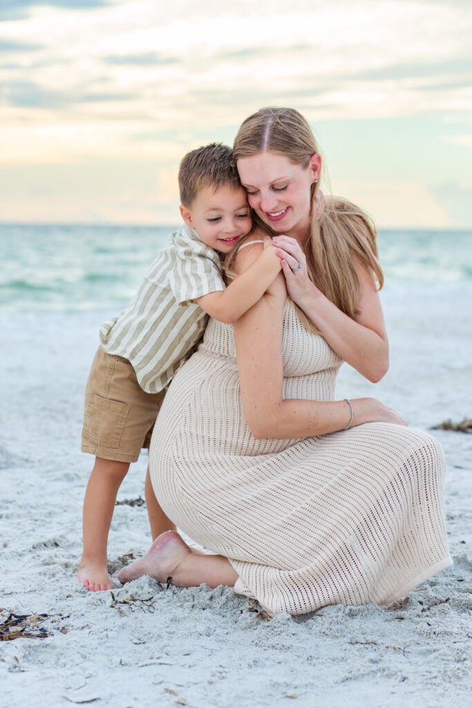 Mother and son kneel on the beach at sunset for their Anna Maria Island photo session