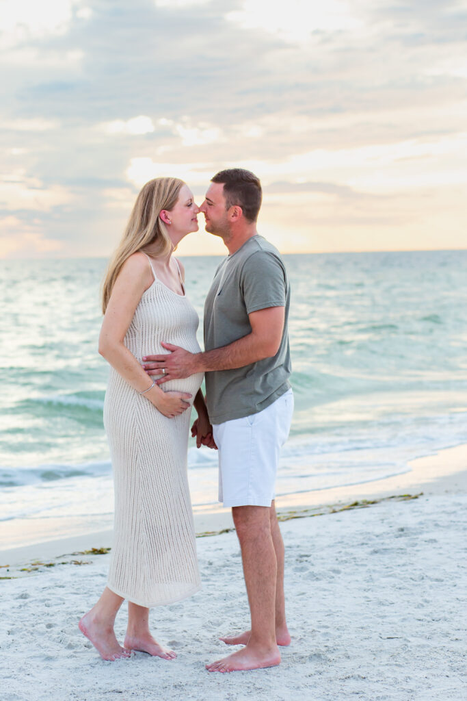 Couple walking on the beach at sunset for their Anna Maria Island maternity session