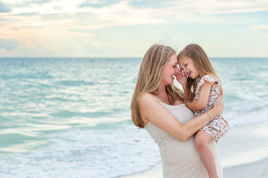 Mother and daughter laughing together on the beach at sunset for their Anna Maria Island photo session