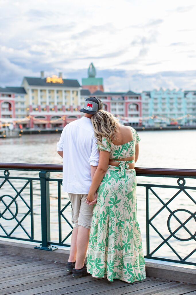 Couple holds hands as they gaze at the view at the Boardwalk for their Disney Engagement Photos