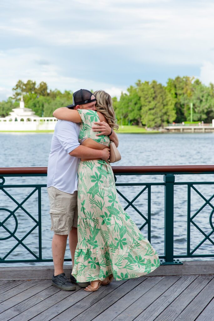 Couple hugging after their Disney Proposal at the Boardwalk in front of the water