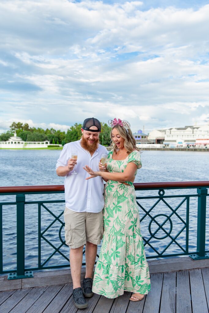 Couple celebrating after their Disney Proposal at the Boardwalk in front of the water