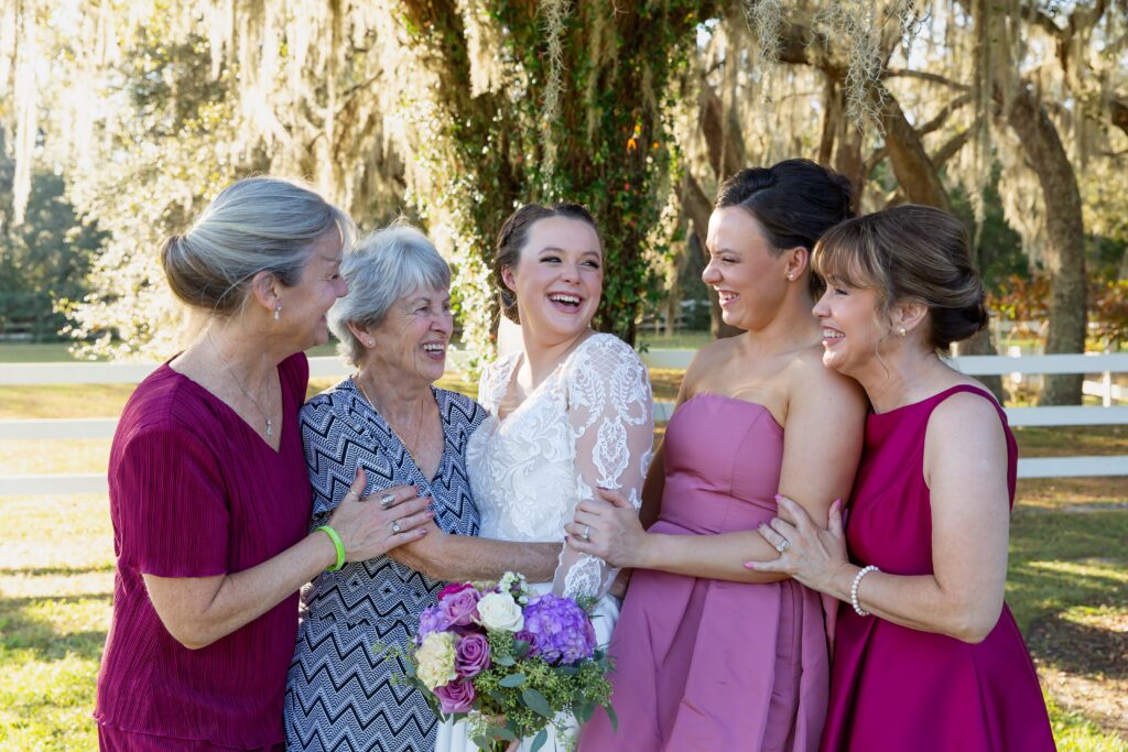 3 Generational photo of grandmother, mom and daughters laughing at Bride's wedding under large tree at Bramble Tree Estate in Orlando, Florida