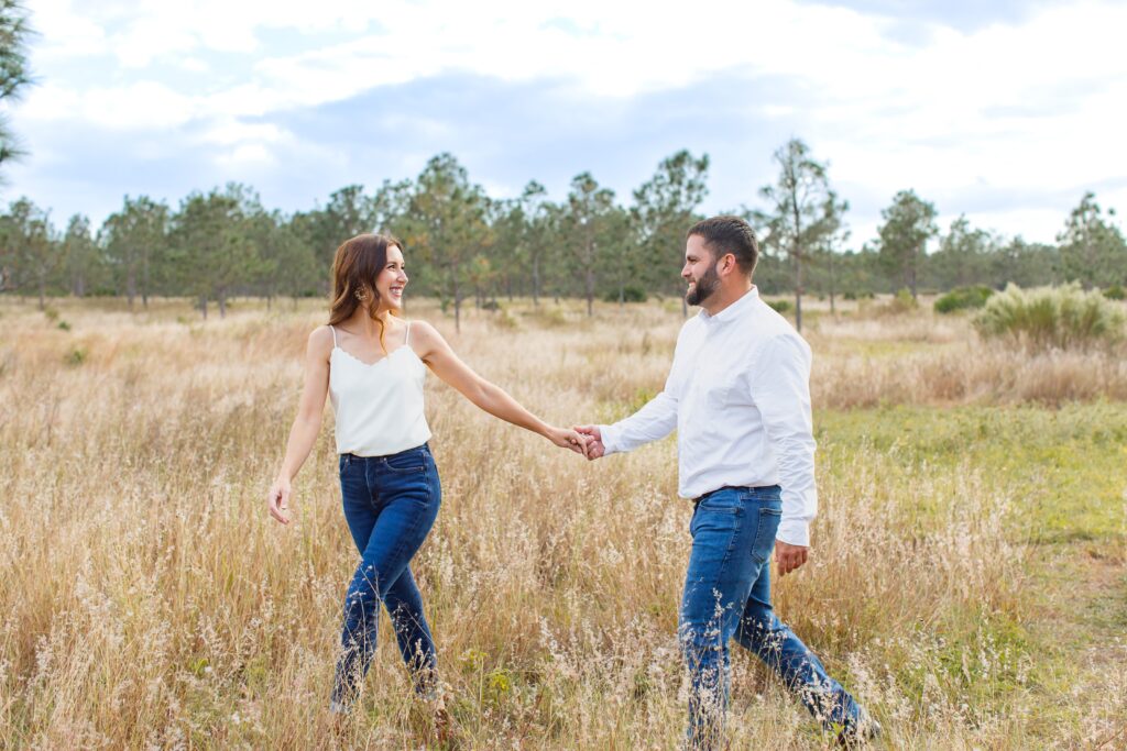 Couple laughing and walking in field for their sunset engagement photos at Lake Louisa State Park in Orlando Florida