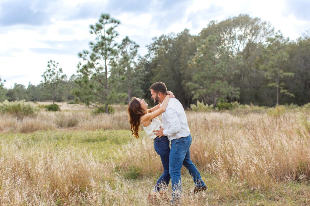 Couple laughing and dancing in field for their engagement photos at Lake Louisa State Park in Orlando Florida