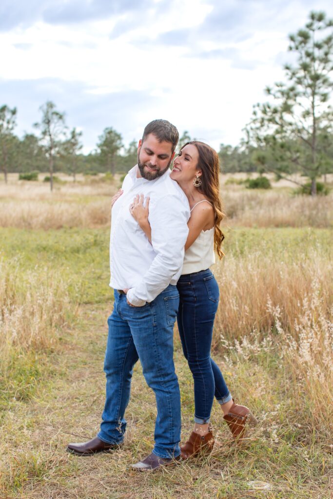 Girl hugging guy in field for their engagement photos at Lake Louisa State Park in Orlando Florida