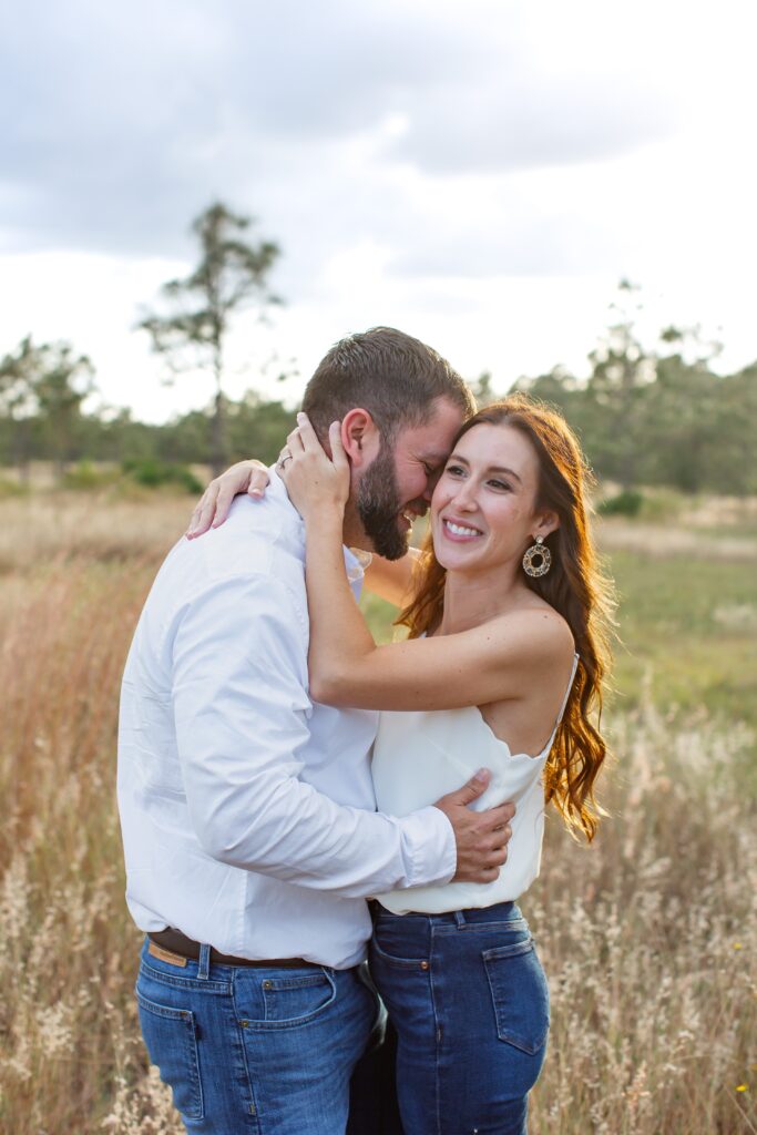 Guy making girl laugh as they stand in a field for their engagement photos at Lake Louisa State Park in Orlando Florida