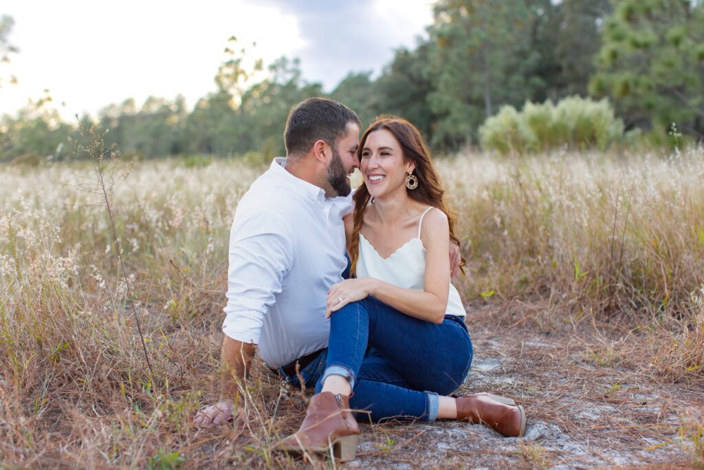 Couple laughing and sitting in field for their engagement photos at Lake Louisa State Park in Orlando Florida