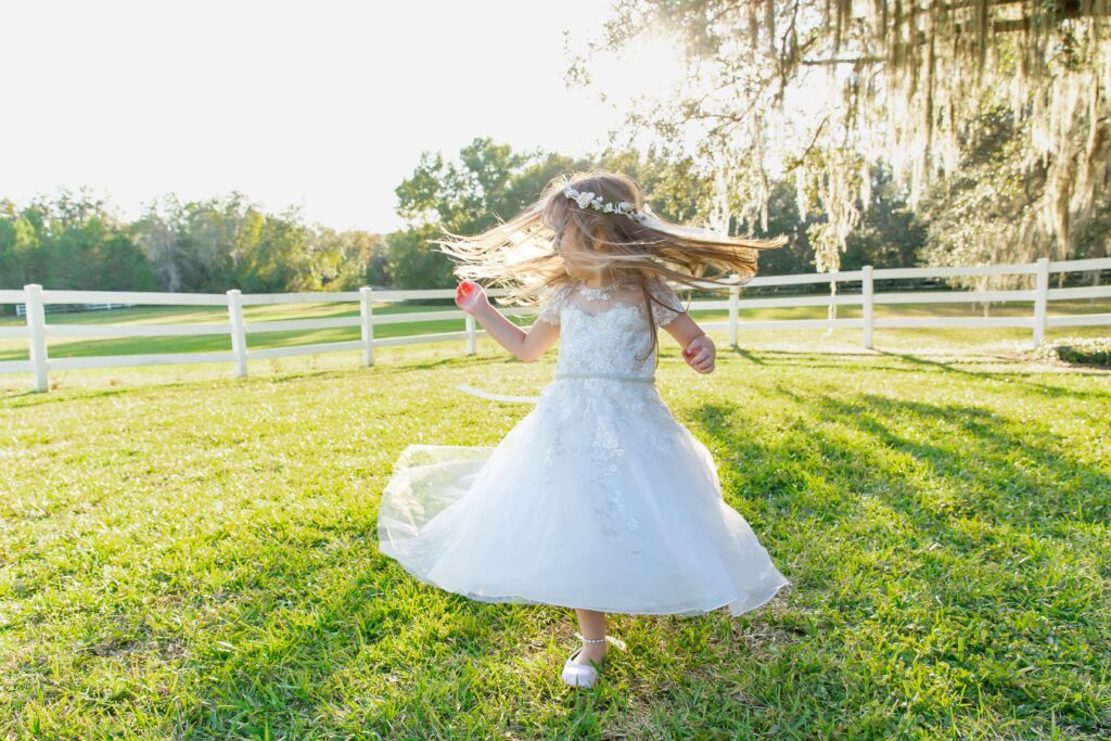 Flower girl spinning under large tree at sunset in open field at Bramble Tree Estate in Orlando, Florida