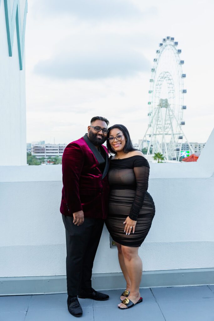 Couple poses together after their proposal on the rooftop of Castle Hotel Orlando in front of the Orlando Wheel at Icon Park