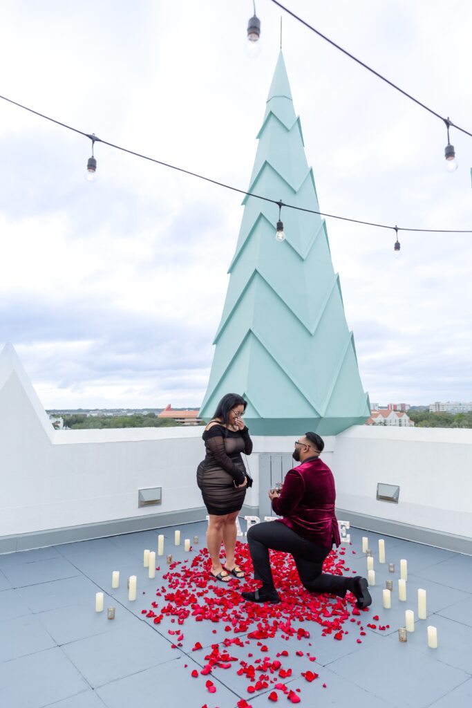 Guy proposes to girl with rose petals, candles, and a marry me sign on the rooftop of Castle Hotel Orlando