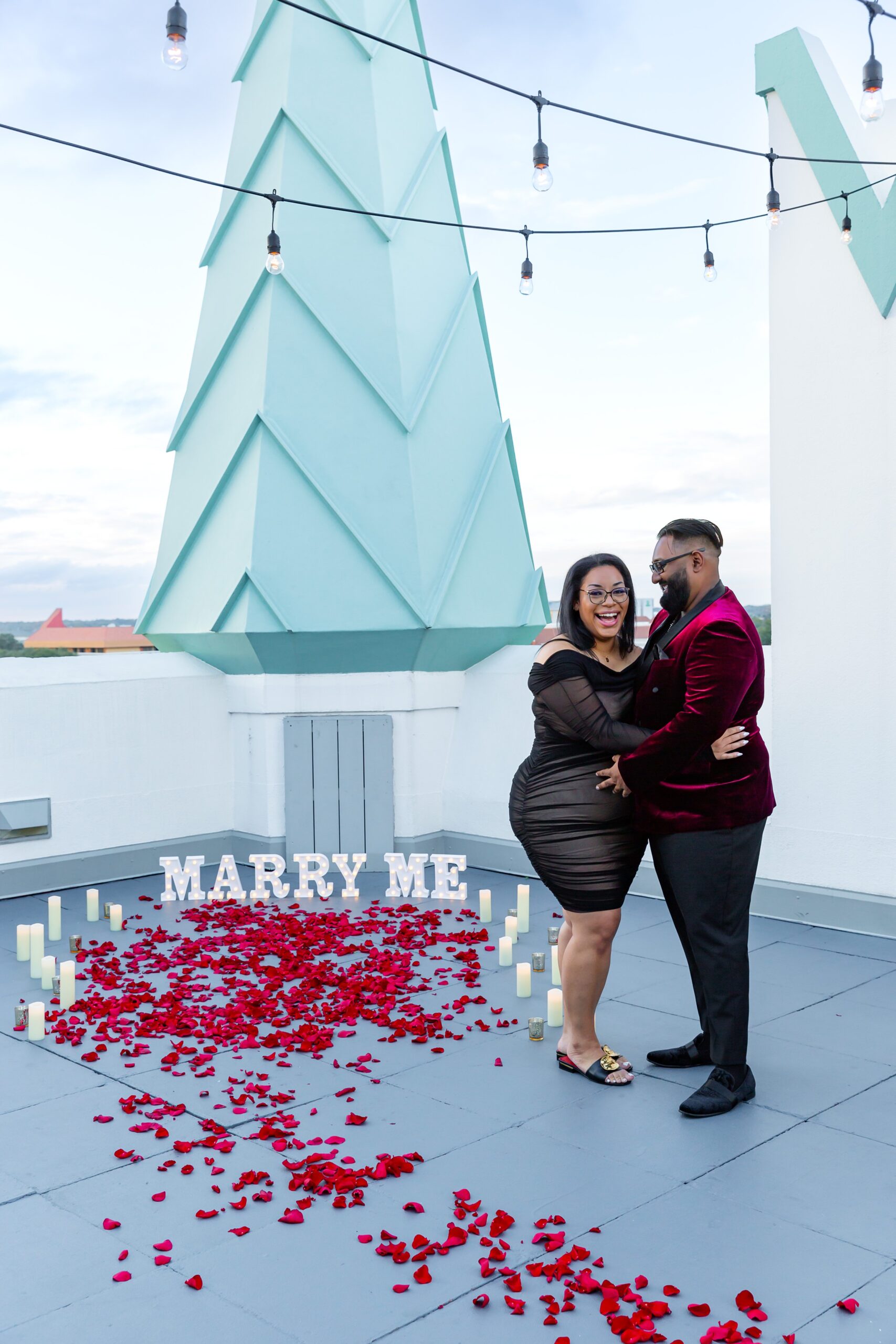 Guy proposes to girl with rose petals, candles, and a marry me sign on the rooftop of Castle Hotel Orlando