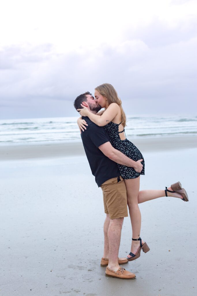 Guy lifts girl and kisses her after he proposes for their New Smyrna Beach Photos
