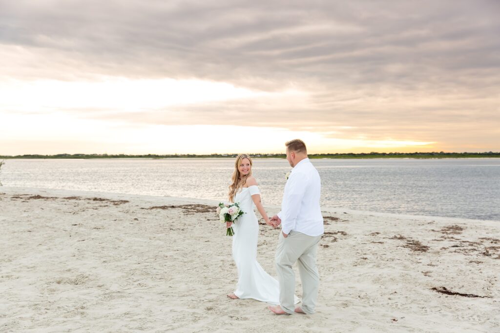 Couple walking on the beach with stunning sunset at their Florida Beach Wedding at Ponce Inlet Beach, Florida