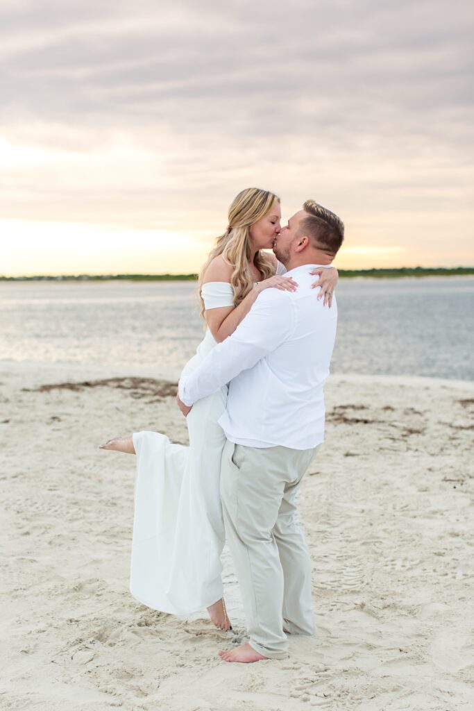 Groom lifting Bride on the beach with stunning sunset at their Florida Beach Wedding at Ponce Inlet Beach, Florida