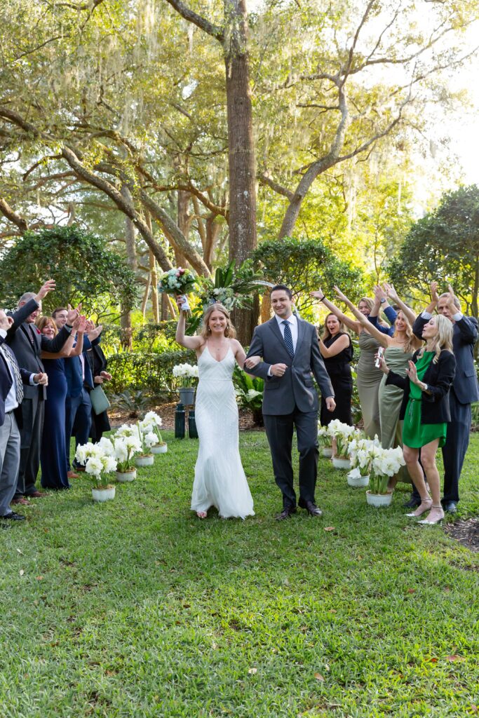 Bride and Groom celebrate after their wedding ceremony while family and friends cheer them on at their back yard wedding in Orlando, Florida