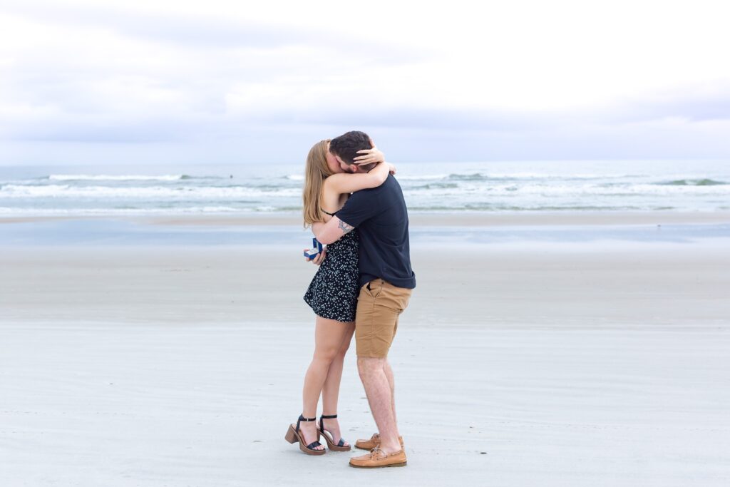 Couple hugs and kisses after beach proposal - New Smyrna Beach Photos