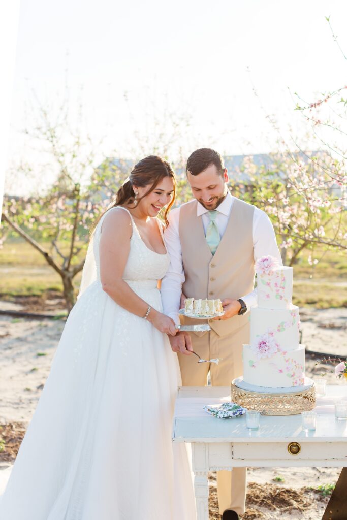 Bride and Groom cut wedding cake in the peach orchard after their wedding at Acres of Grace Wedding Venue in Central Florida