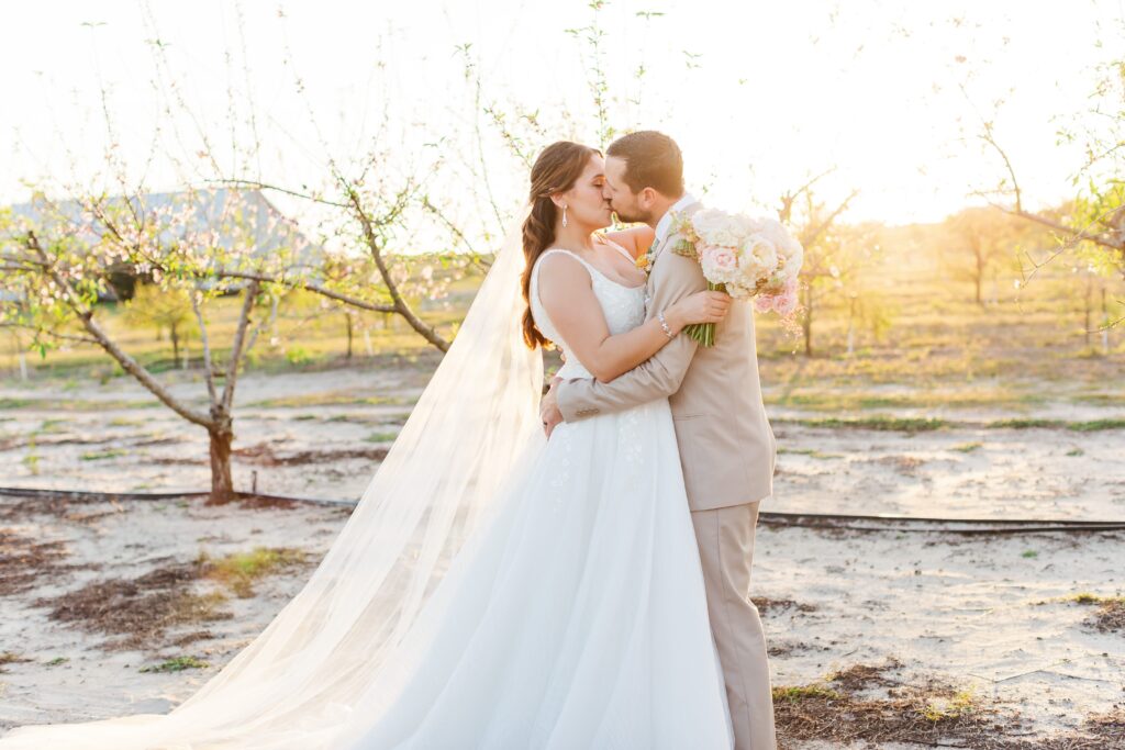Bride and Groom kiss in the peach orchard after their wedding at Acres of Grace Wedding Venue in Central Florida