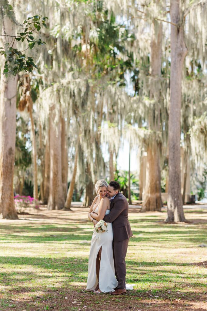 Couple hugging under beautiful live oak trees and moss at Kraft Azalea Garden Wedding in Orlando, Florida