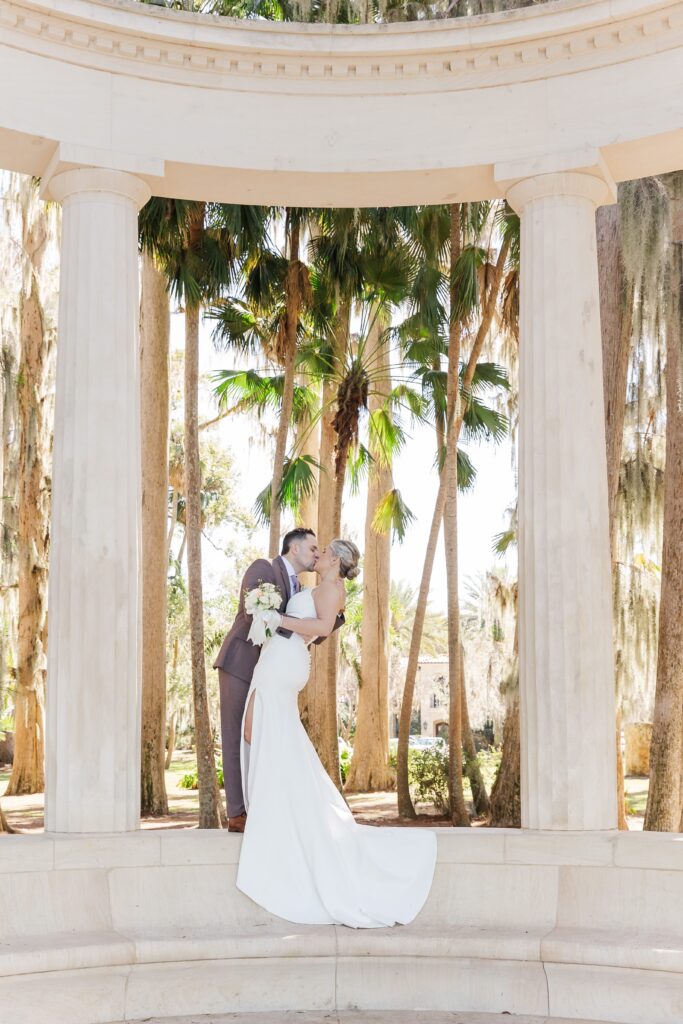 Groom dips Bride at the exedra columns at Kraft Azalea Garden Wedding in Orlando, Florida