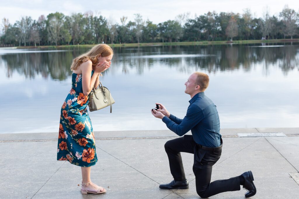 Guy proposes to girl by the water in front of the Celebration Bohemian Hotel at sunset in Celebration, Florida