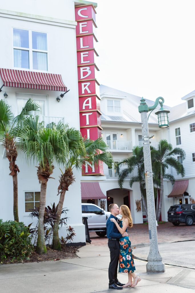 Couple kisses in front of the Celebration Bohemian Hotel for their engagement photos at sunset in Celebration, Florida