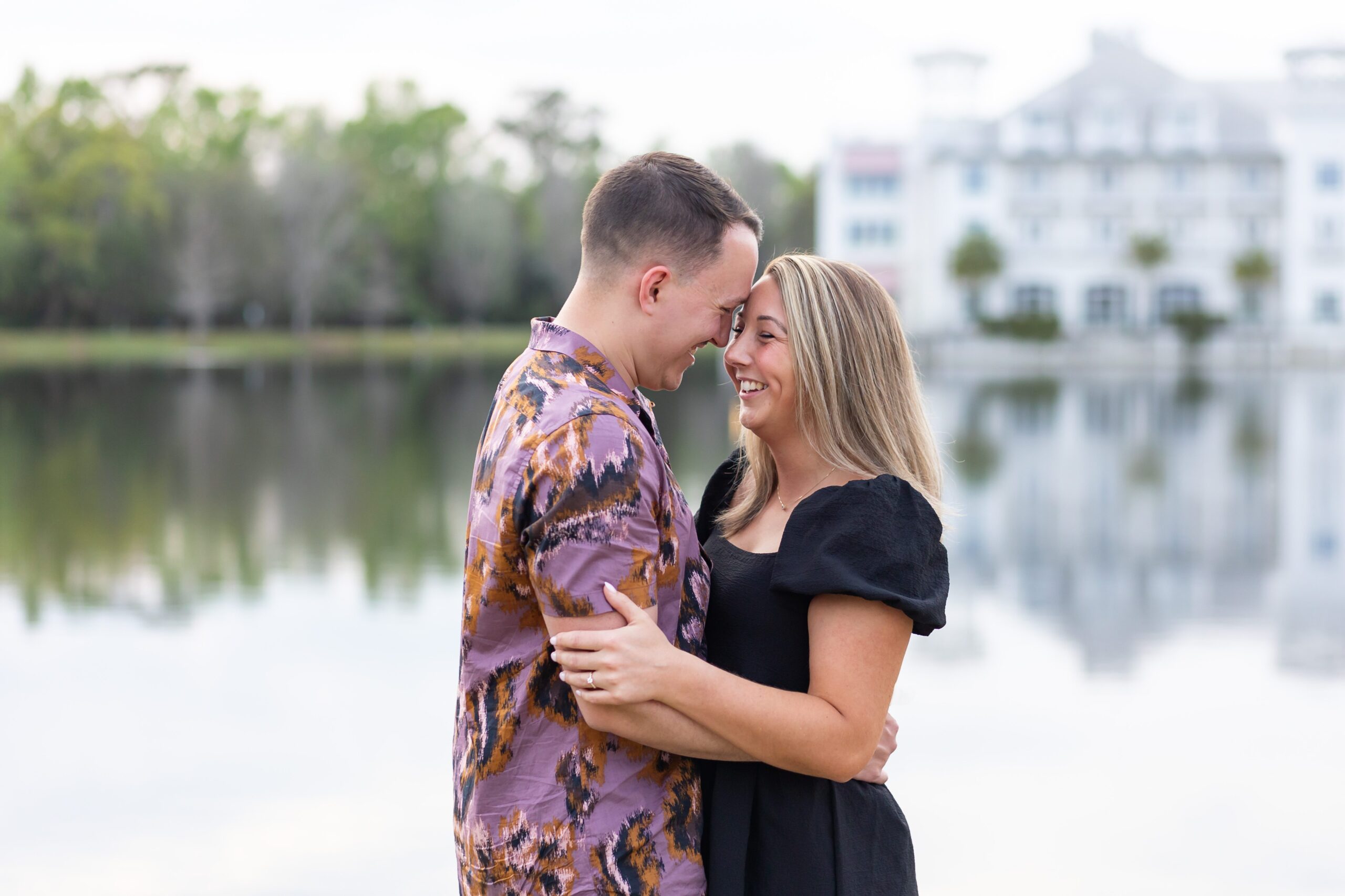 Couple snuggles together for their engagement photos in front of the Bohemian Hotel in Celebration, Florida