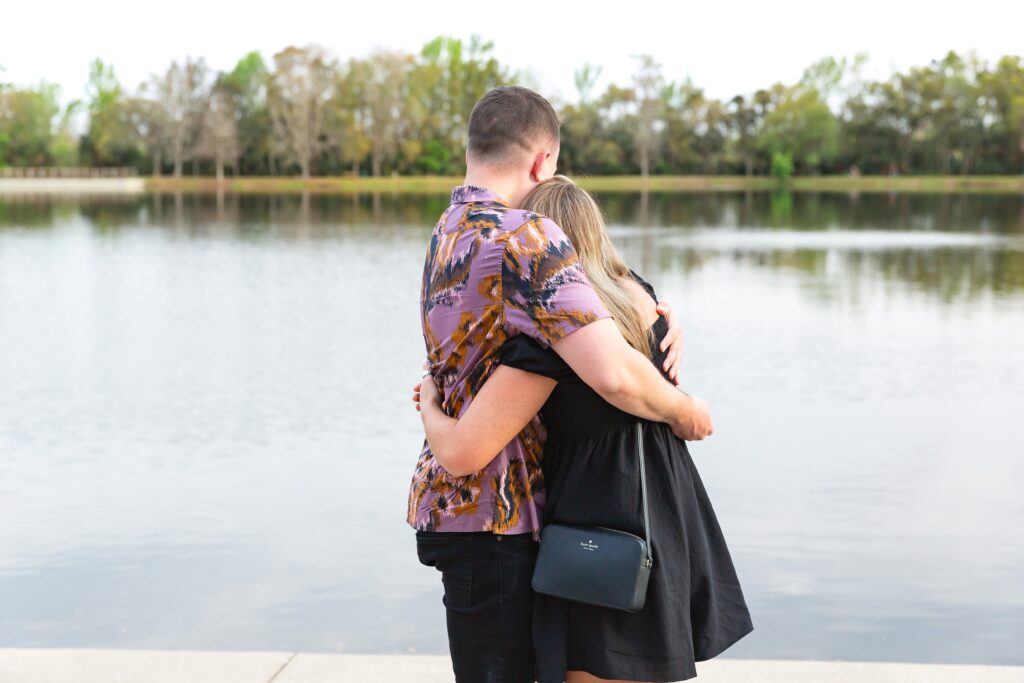 Couple hugs after Guy proposes to girl in front of the water on Front Street in Celebration, Florida