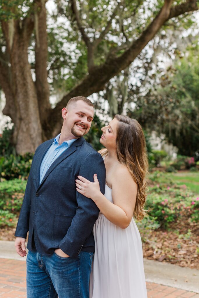 Couple looks at each other and smiles in front of Cypress Grove Estate House for their Orlando Engagement Photos at Cypress Grove Park in Orlando