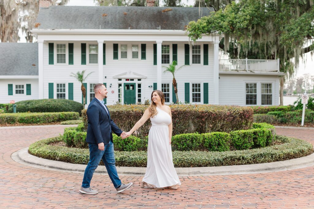 Couple walks in front of Cypress Grove Estate House for their Orlando Engagement Photos at Cypress Grove Park in Orlando