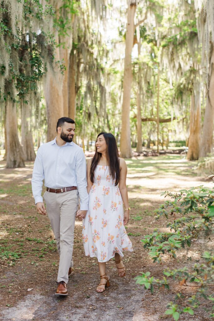 Couple walks and holds hands for their engagement photos at Kraft Azalea Garden in Winter Park, FL