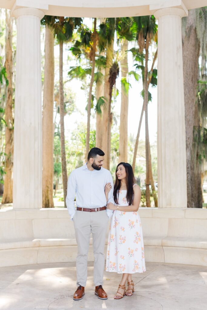 Couple smiles at each other for their engagement photos at Kraft Azalea Garden in Winter Park, FL