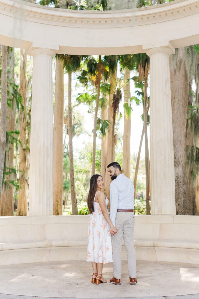 Couple holds hands in front of the exedra for their engagement photos at Kraft Azalea Garden in Winter Park, FL