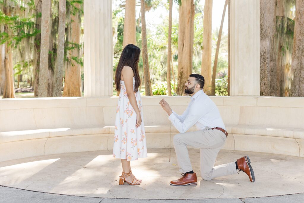 Guy down on one knee proposing to girl at Kraft Azalea Garden in Winter Park, FL