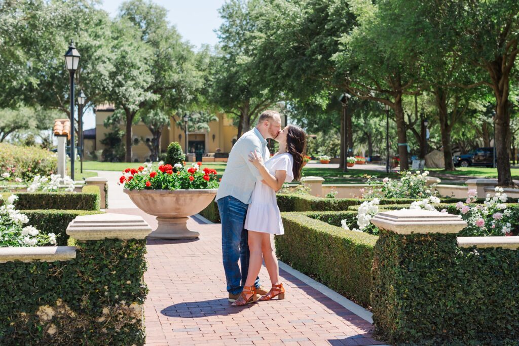 Couple kisses in front of rose Garden at Rollins College in Winter Park, Florida for their engagement photos with Orlando Engagement Photographer Amy Britton Photography