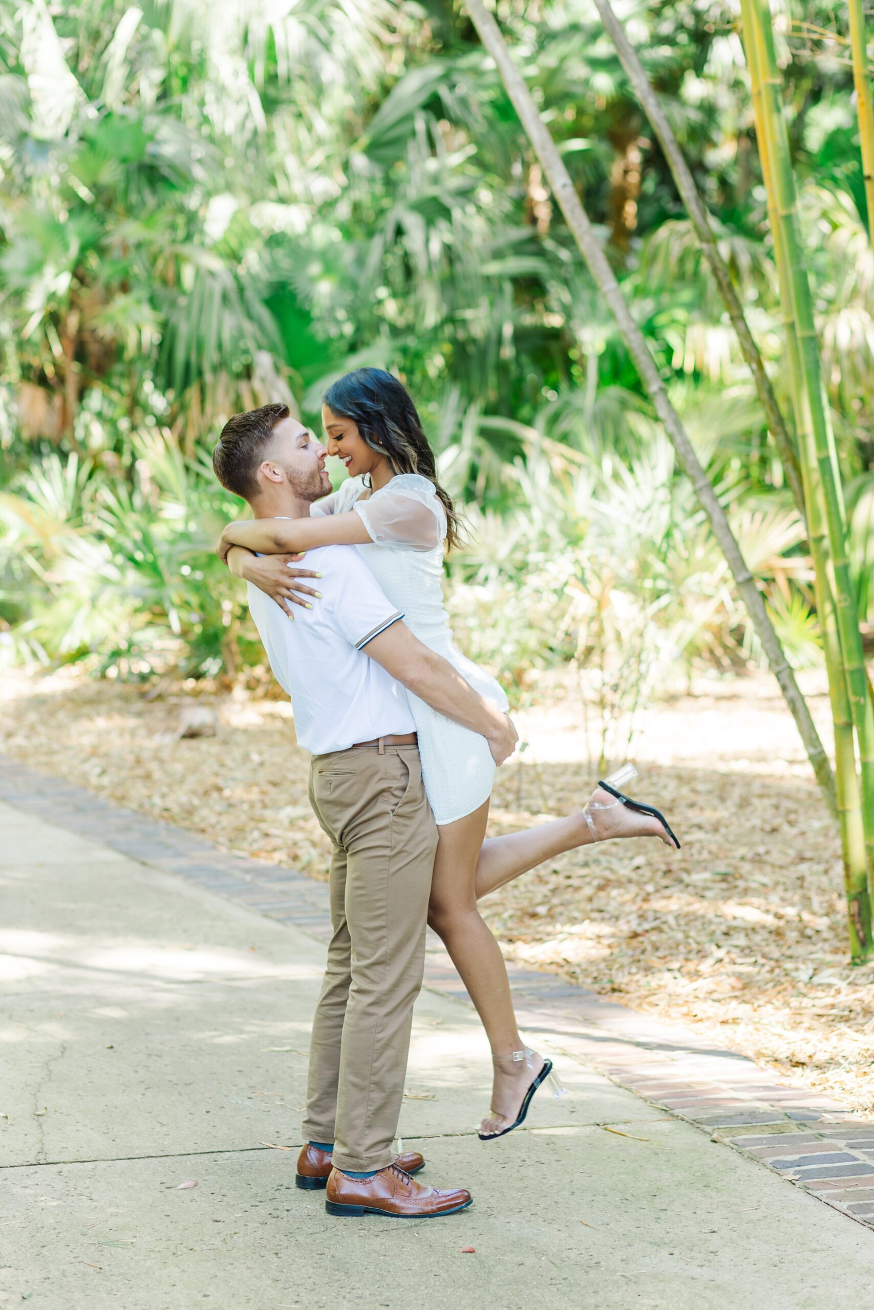 Guy lifts girl up in front of large bamboo for their engagement photos at Leu Gardens in Orlando, Florida