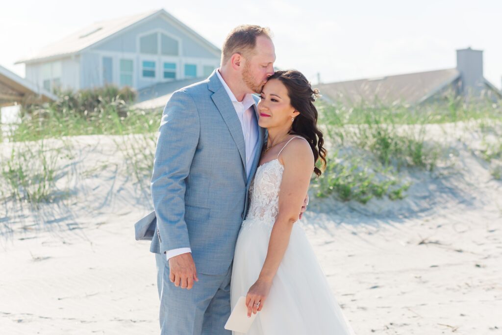 Groom kisses Bride's forehead at their first look at Vilano Beach for their St. Augustine beach wedding