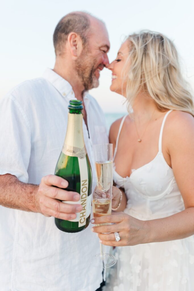 Couple toasts with champagne on the beach for their anniversary photos with their New Smyrna Beach Photographer