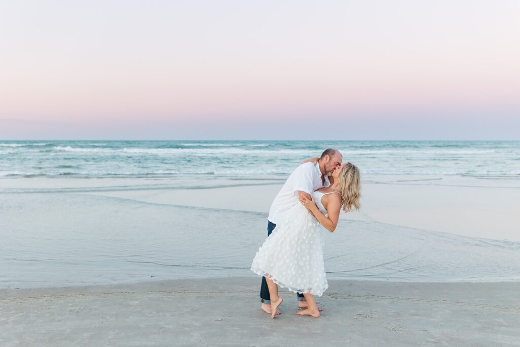 Guy dips girl on the beach at sunset for their anniversary photos with their New Smyrna Beach Photographer